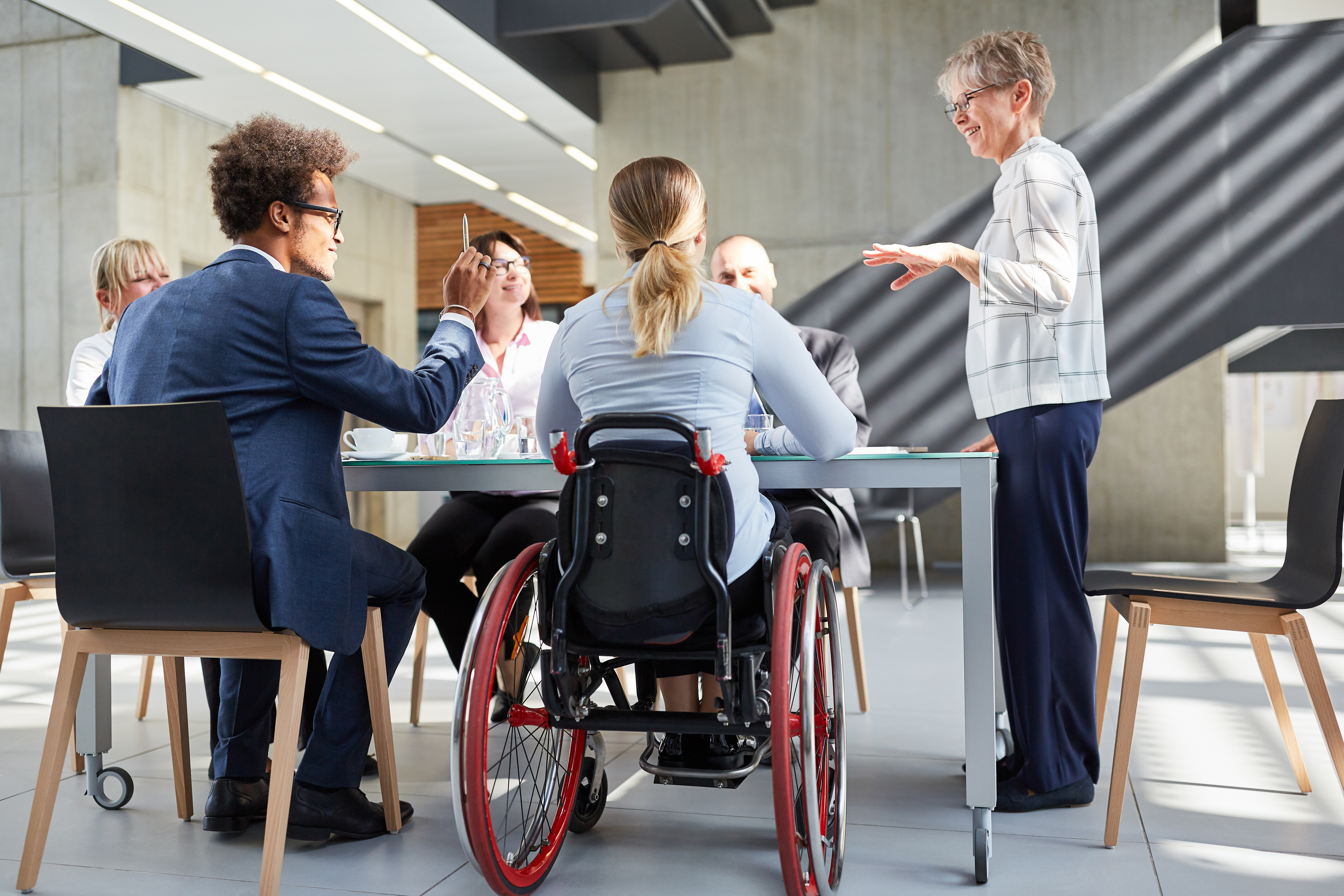 Geschäftsleute im Meeting mit Kollegin im Rollstuhl