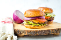 horseradish burgers with sliced onion on a wood cutting board