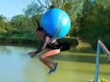 Sauter dans un lac avec un ballon de gymnastique au dos