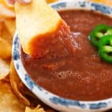 Dipping tortilla chip into salsa.