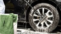 Man washing  soapy car tire and wheel with brush