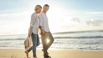 Mature couple walking on the beach at sunset or sunrise.