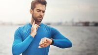 Outdoor, running and man with heart rate on smart watch for exercise, wellness and digital health stats at ocean. Technology, mo