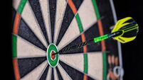 Green and black dart in the bullseye of a dartboard.