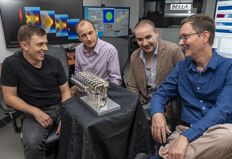 Four members of the BELLA team in an office sitting in chairs around the new gas injector system.