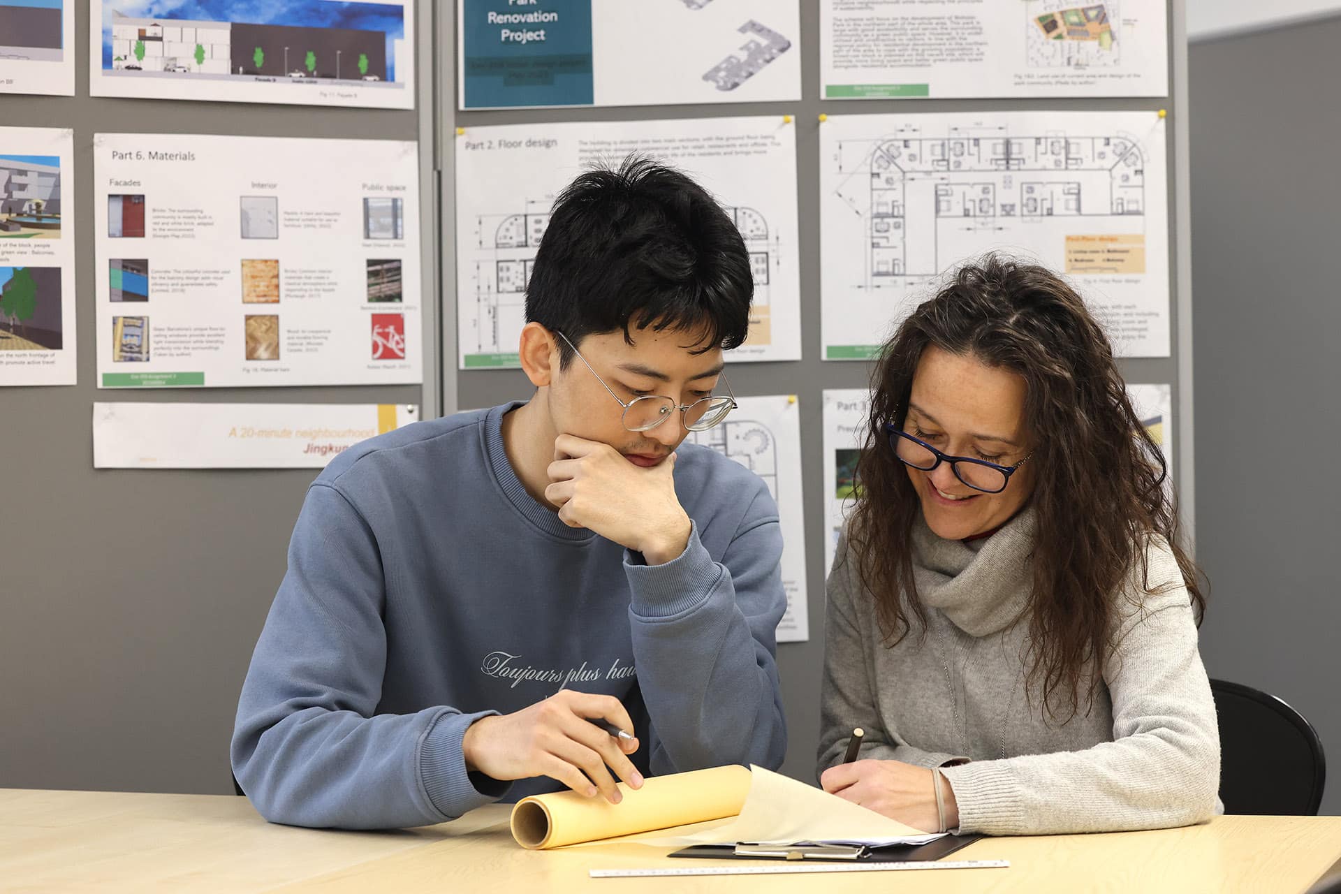 Student sitting looking at a book with a teacher