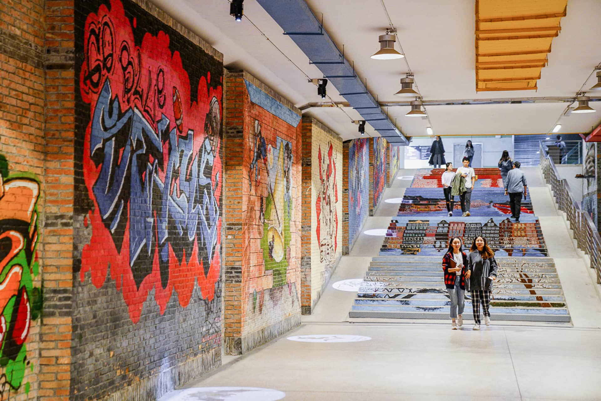 Students walking through subway tunnel with graffiti at XJTLU