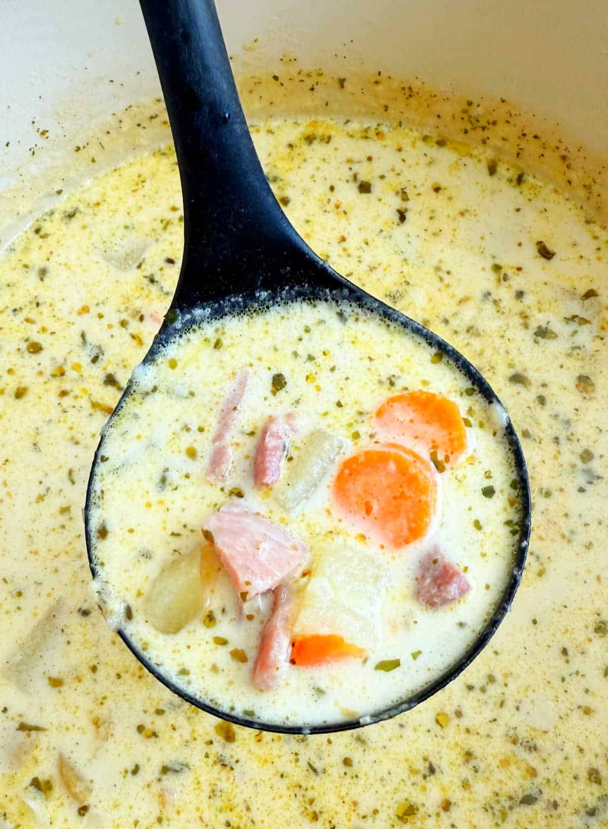 ham potato soup in ladle over dutch oven.