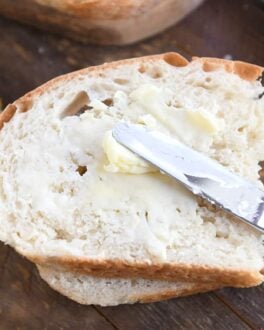 spreading butter on half slice of peasant bread with butter knife