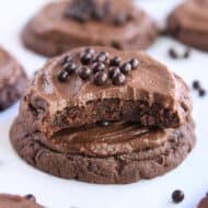 Half of chocolate cookie stacked on another cookie on white parchment paper.