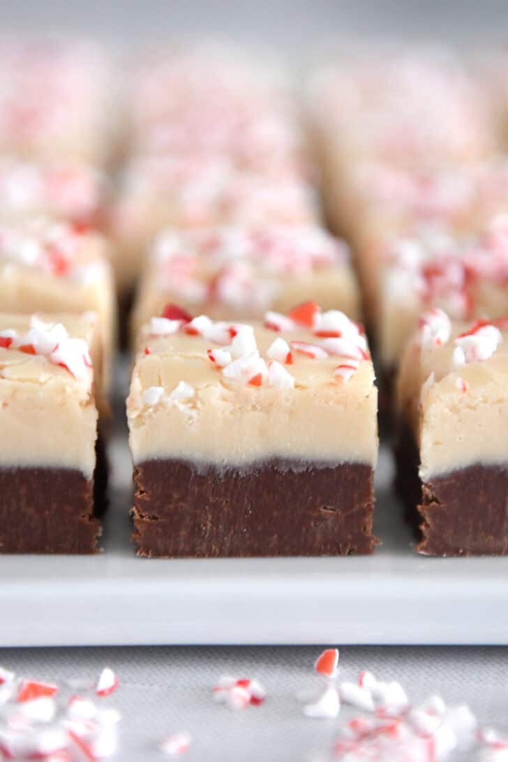 Close up view of layered piece of peppermint bark fudge on white tray.