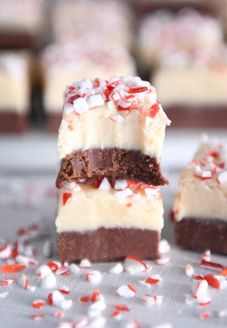 Two pieces of peppermint bark fudge stacked. Top piece has bite taken out of half.