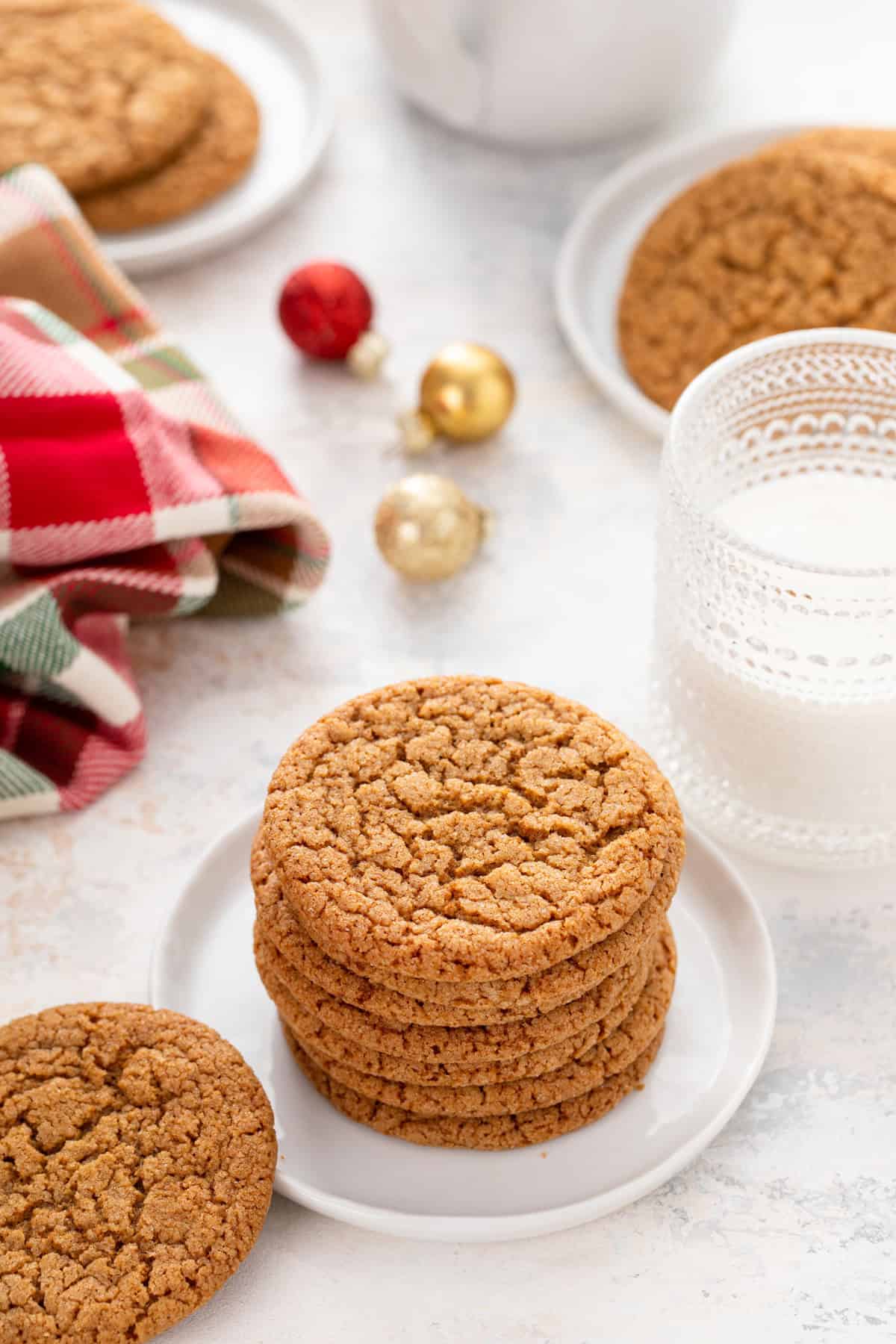 White plates holding gingersnap cookies around a glass of milk.