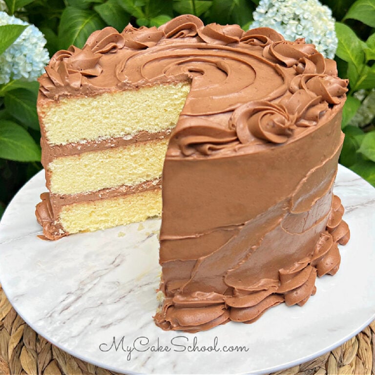 Sliced Yellow Velvet Cake with chocolate cream cheese frosting on a pedestal.