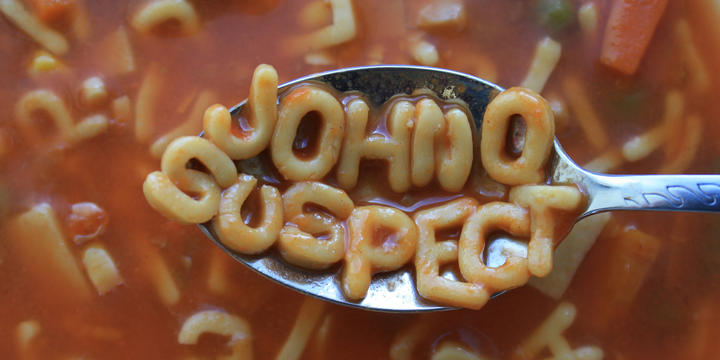 A spoon hovers above a bowl of alphabet soup. On the spoon are the letters JOHN Q SUSPECT. 