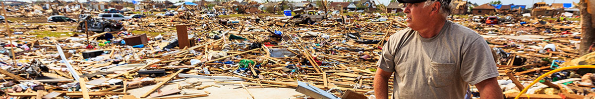 Man standing among the wreckage of homes.