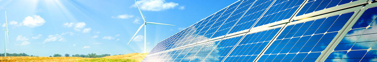 Blue sky. Green grass. Wind mill. To the right: solar panels