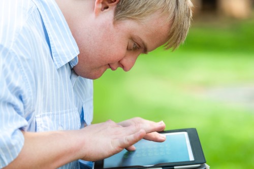 Kid with down syndrome playing on tablet.