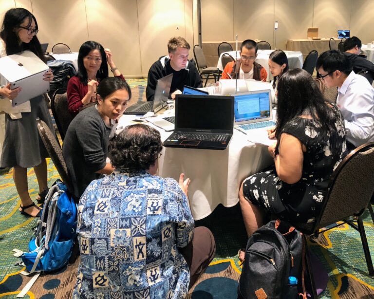 a group of people sitting around a table at a SCEC workshop