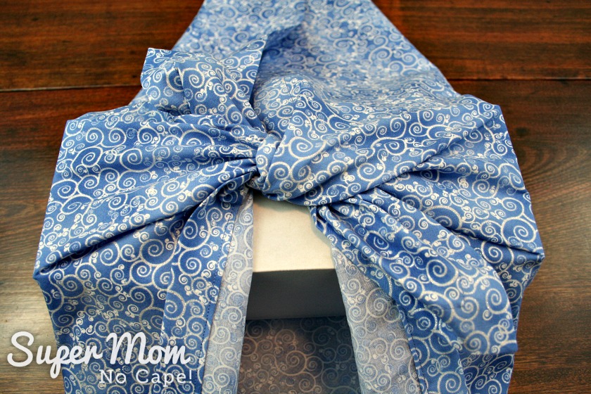 Tying first knot in blue Christmas furoshiki