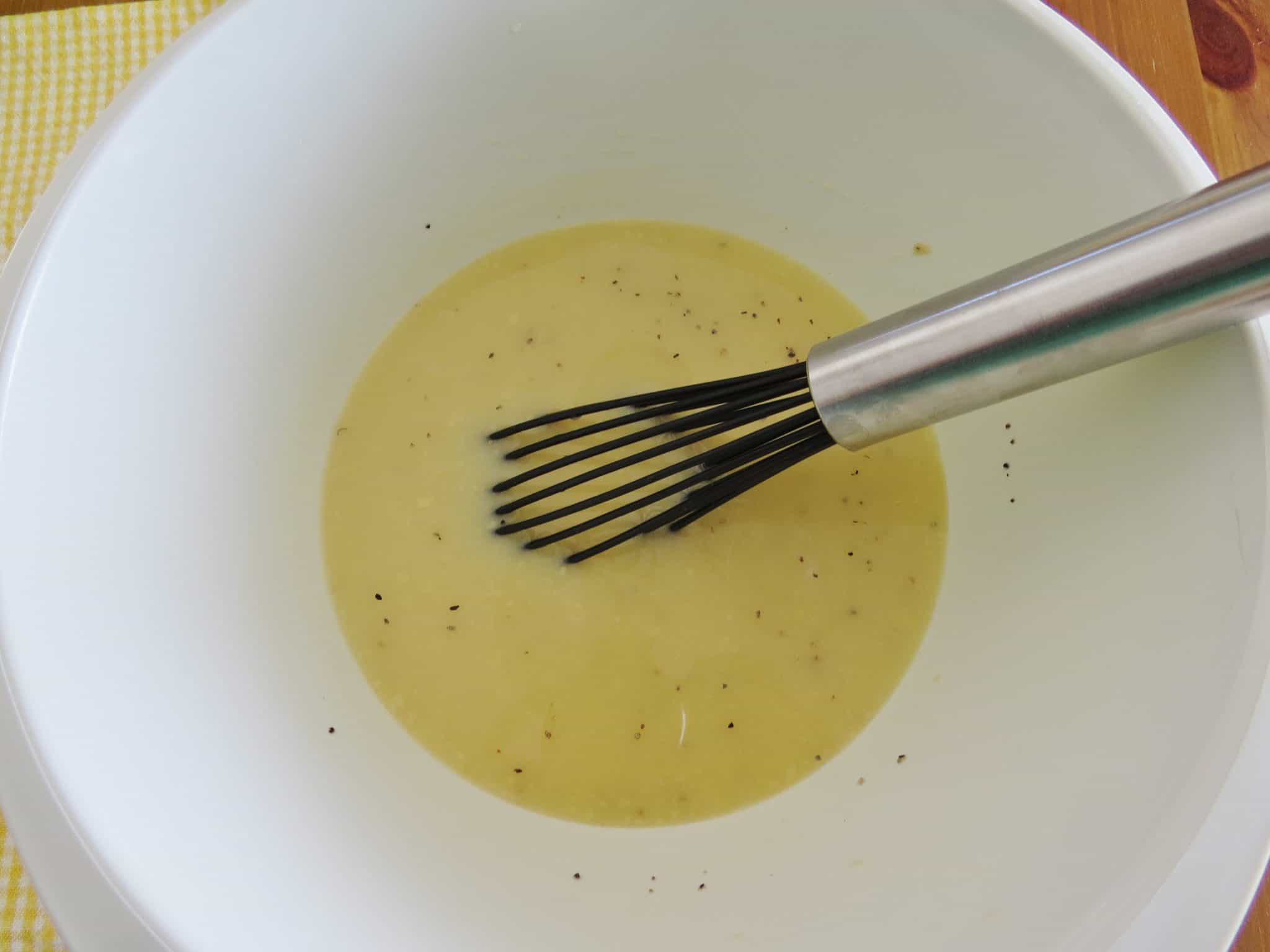 milk and self rising flour whisked together in a white bowl.