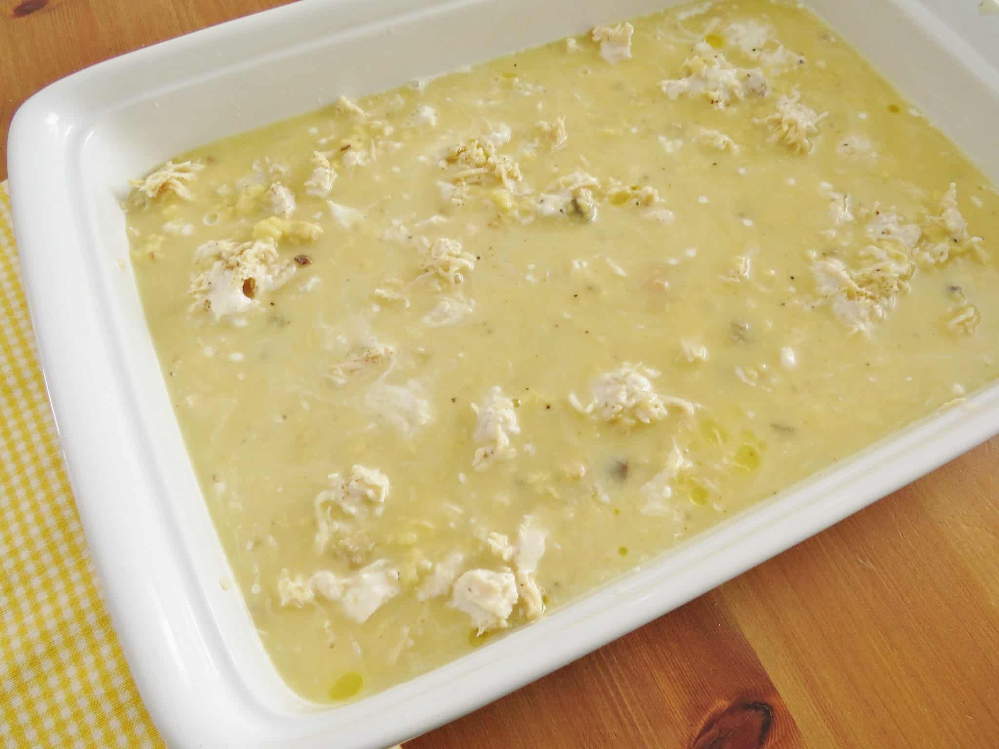 flour and milk mixture poured over shredded chicken in rectangular white baking dish.