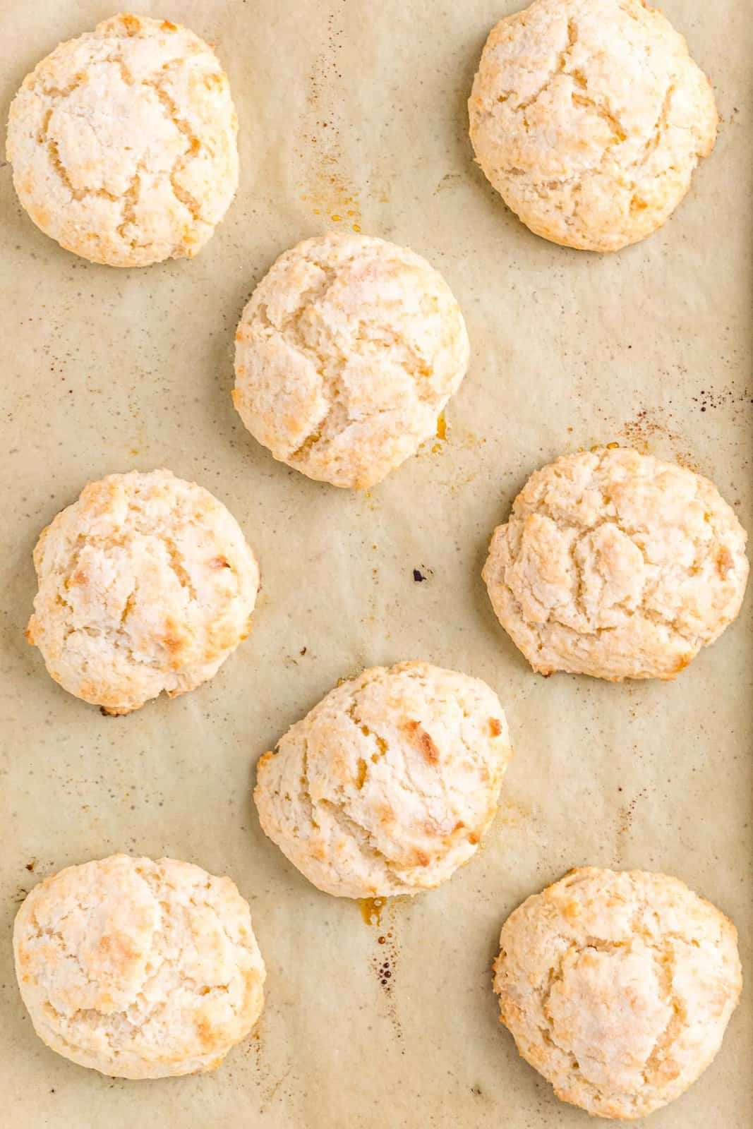 fully baked shortcakes shown on a brown parchment paper lined baking sheet.