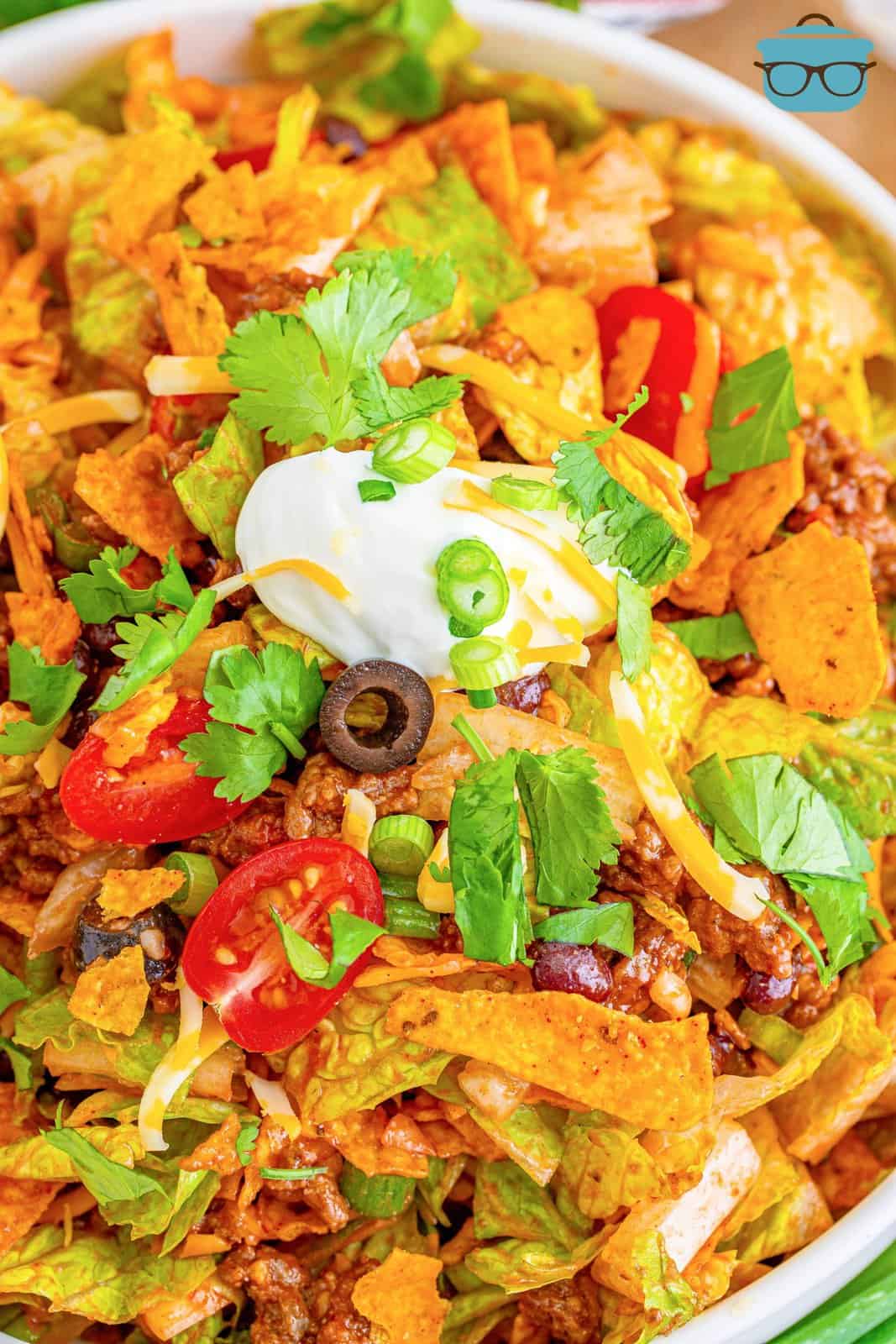 white bowl filled with taco salad topped with a dollop of sour cream.