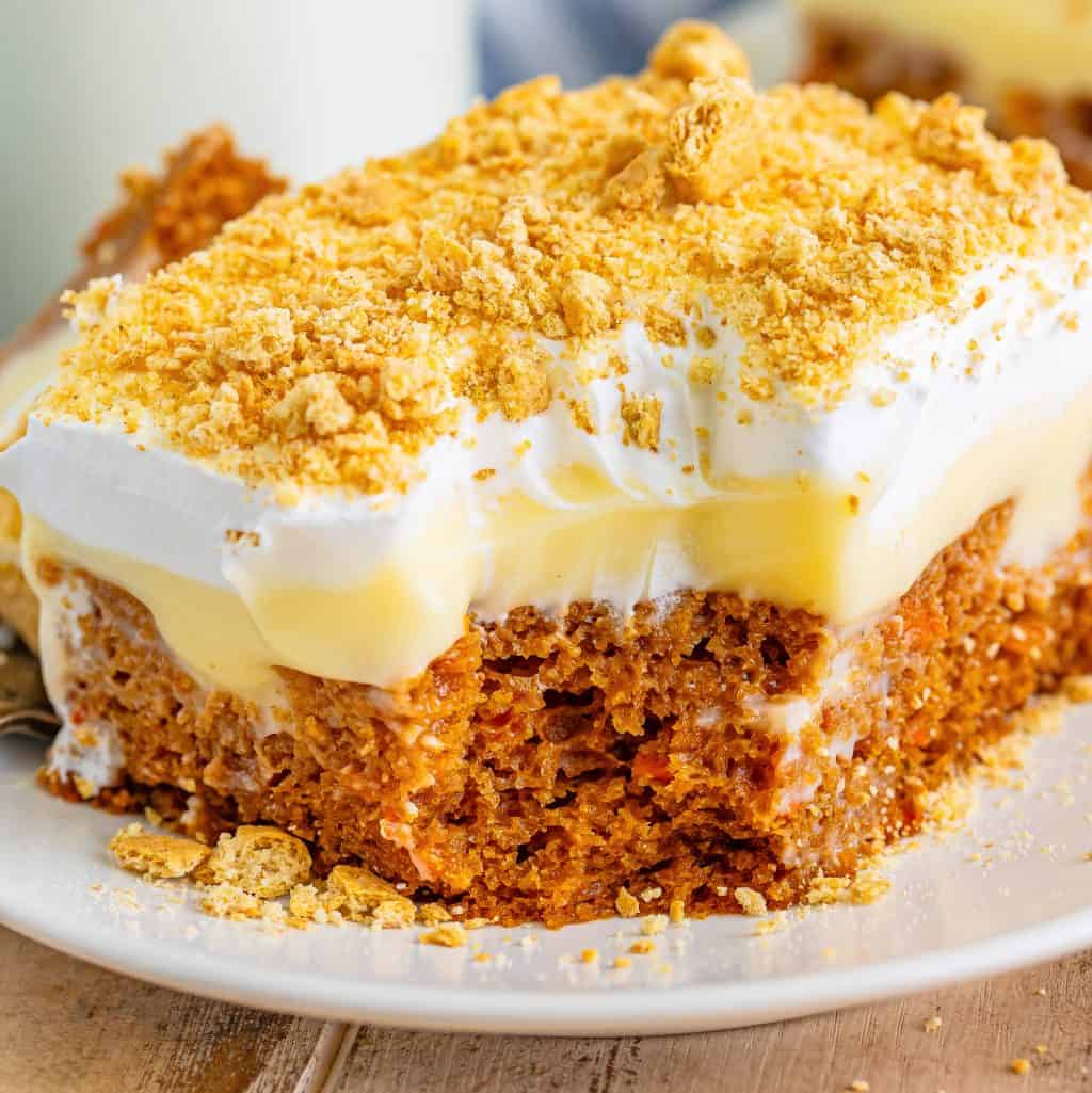 A large slice of Carrot Poke Cake with a bite missing.