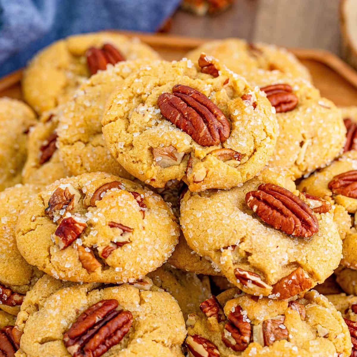 Square image close up of Butter Pecan Cookies on wooden platter.