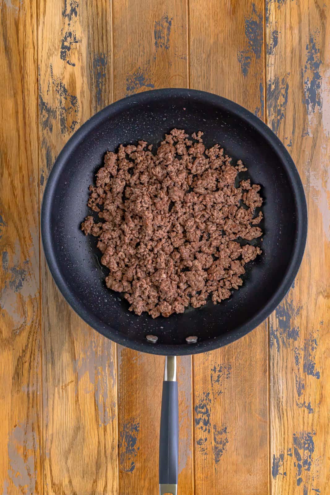 cooked and crumbled ground beef in a skillet.