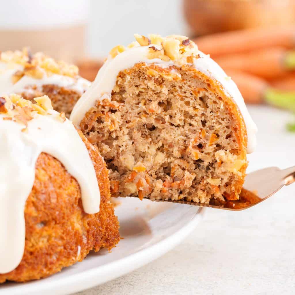 A slice of Carrot Bundt Cake being removed from the serving plate.