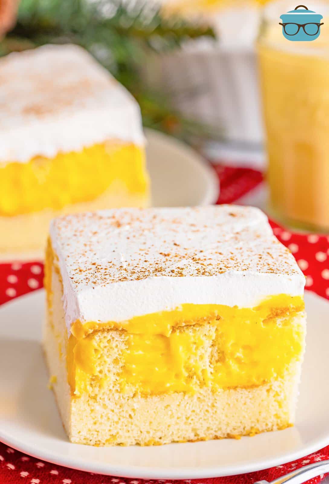 A slice of Eggnog Poke Cake on a white small serving plate.