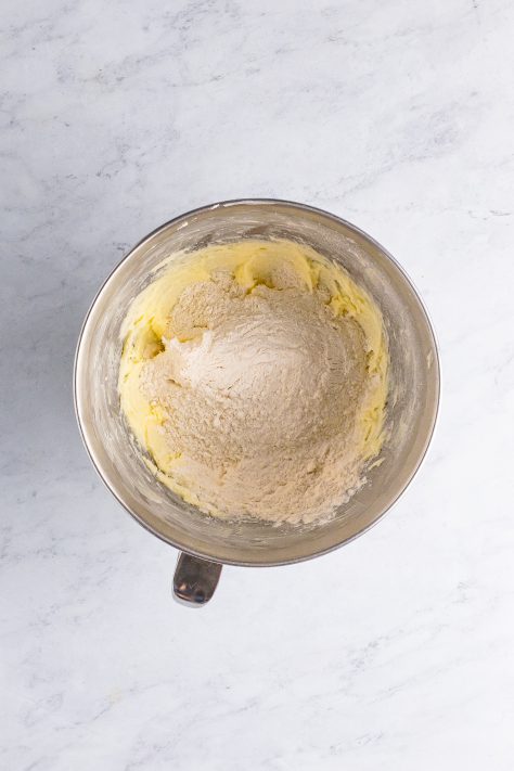 Flour on top of creamed butter and sugar in a mixing bowl.