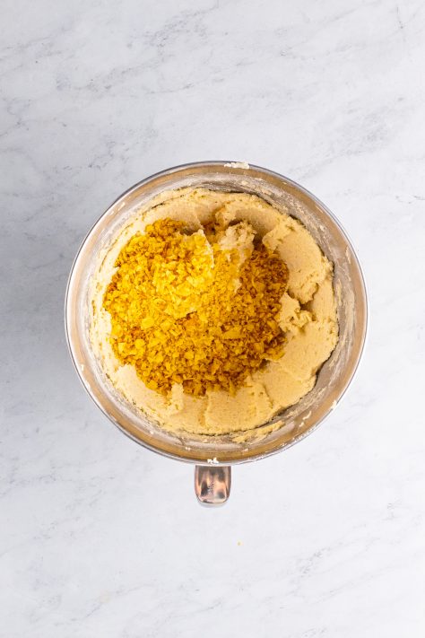 Crushed potato chips being added to a cookie dough mix.