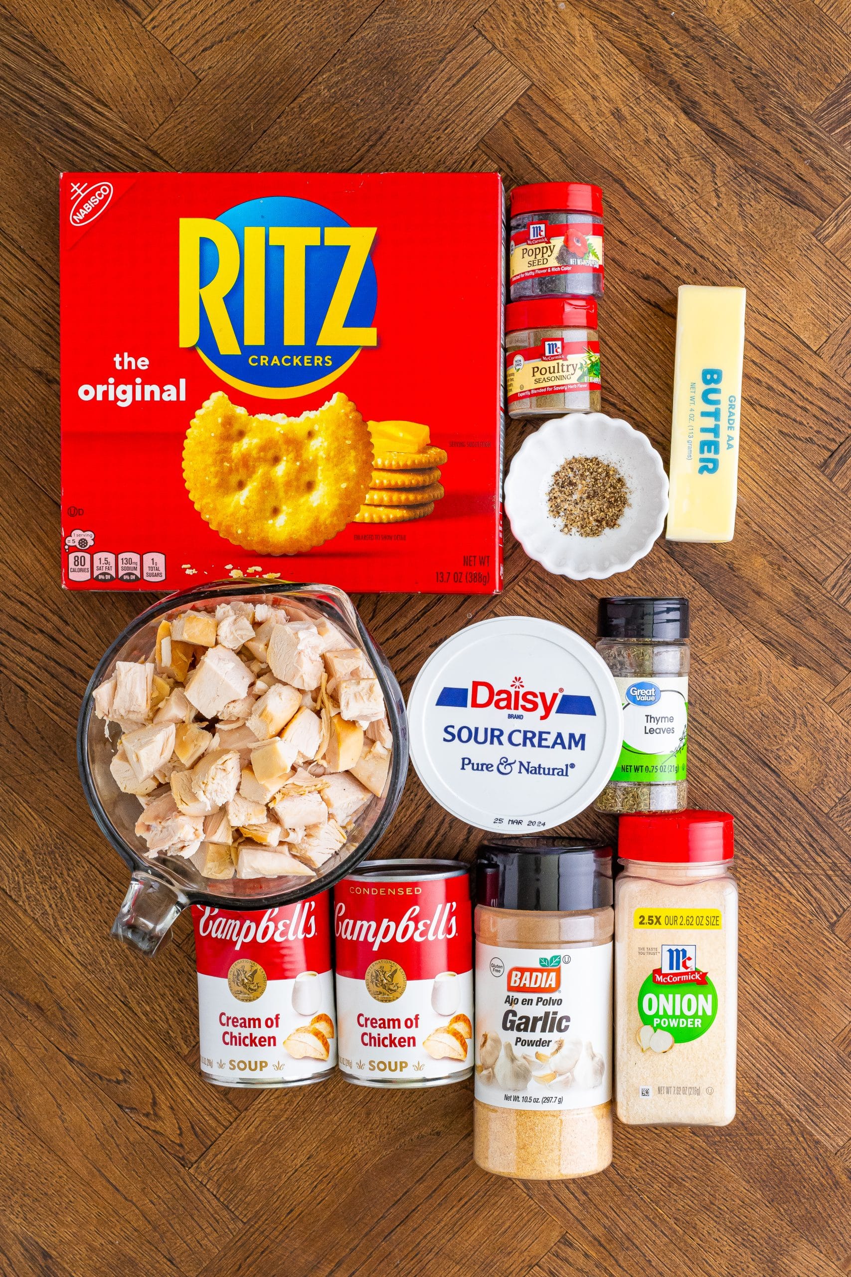 Ritz crackers, butter, chicken, cream of chicken soup, onion powder, garlic powder, sour cream, poultry seasoning, black pepper, thyme, and poppy seeds. 