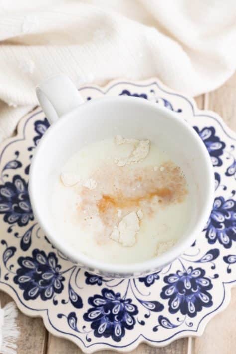 A mug with flour, sugar, and baking powder, vanilla and milk.