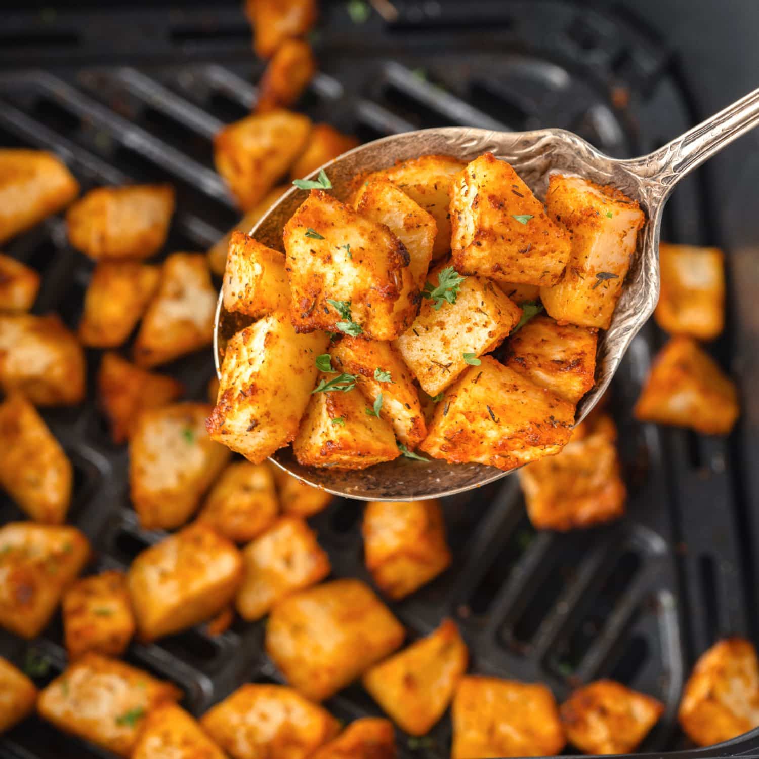 A scoop of Air Fryer Home Fries above the basket.