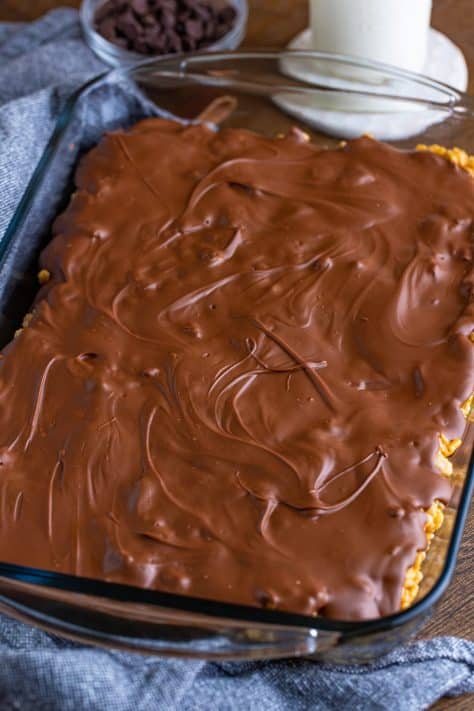 Chocolate mixture on top of cereal mixture in a pan.