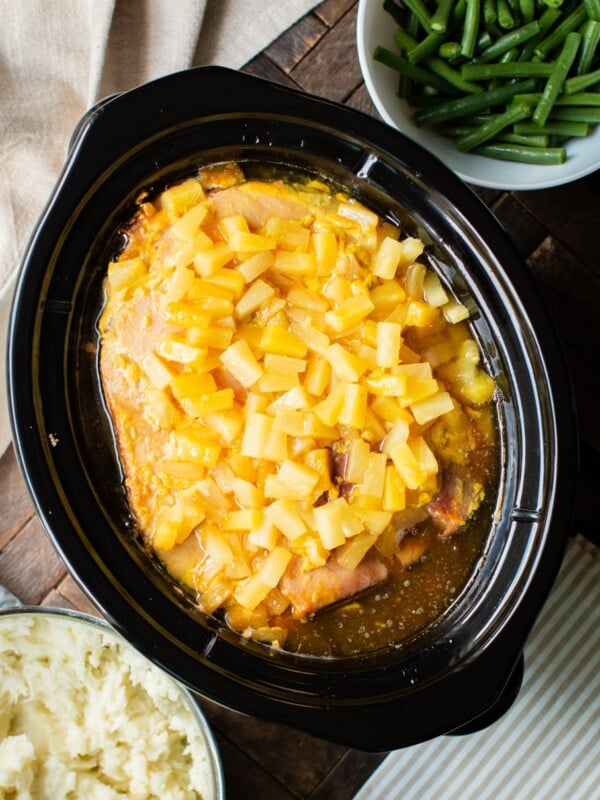 pineapple ham in slow cooker with mashed potatoes and green beans on the side.