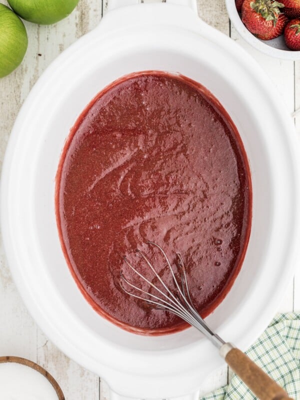 cooked strawberry applesauce with whisk in it.