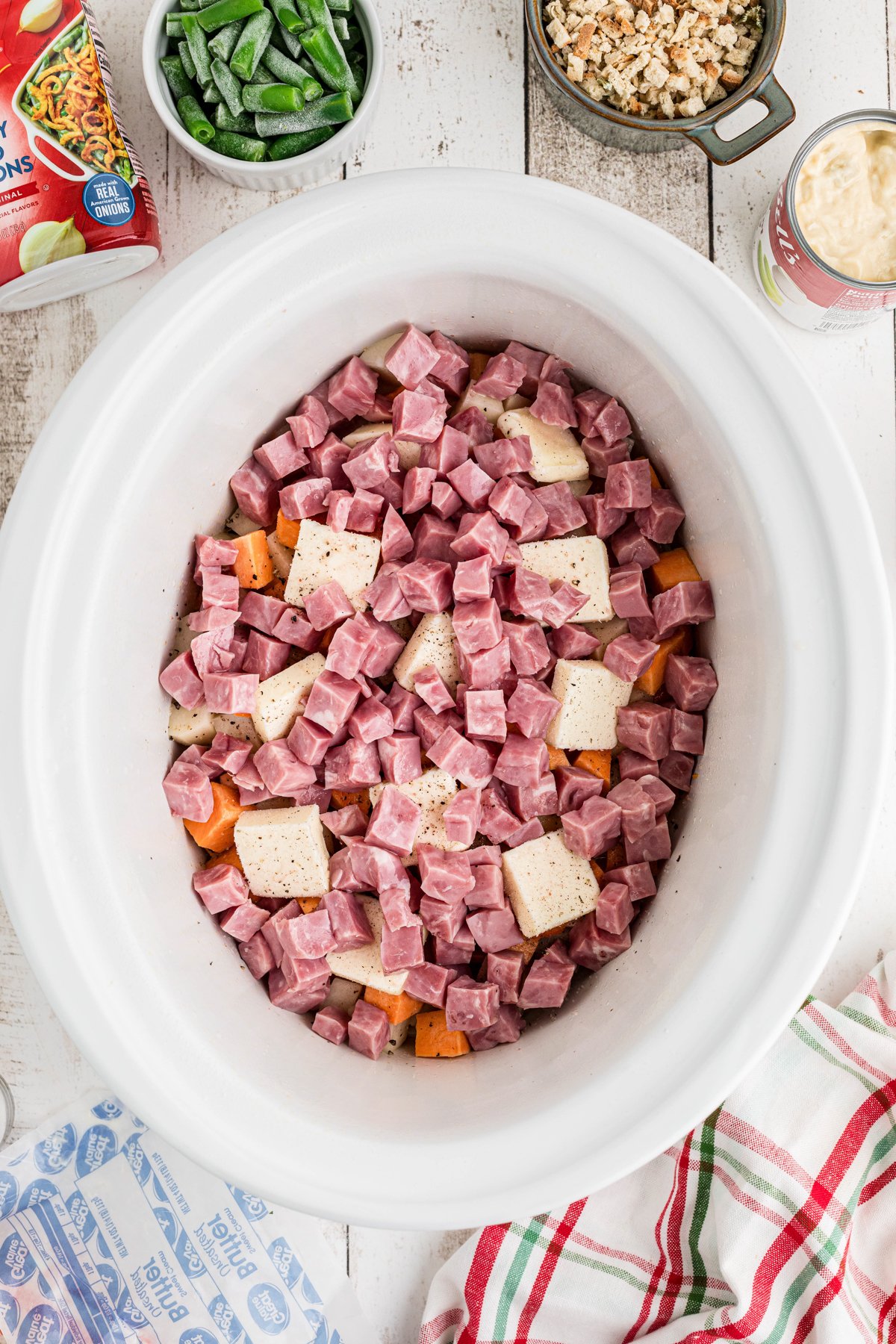 Cubed ham added to potatoes in a crockpot