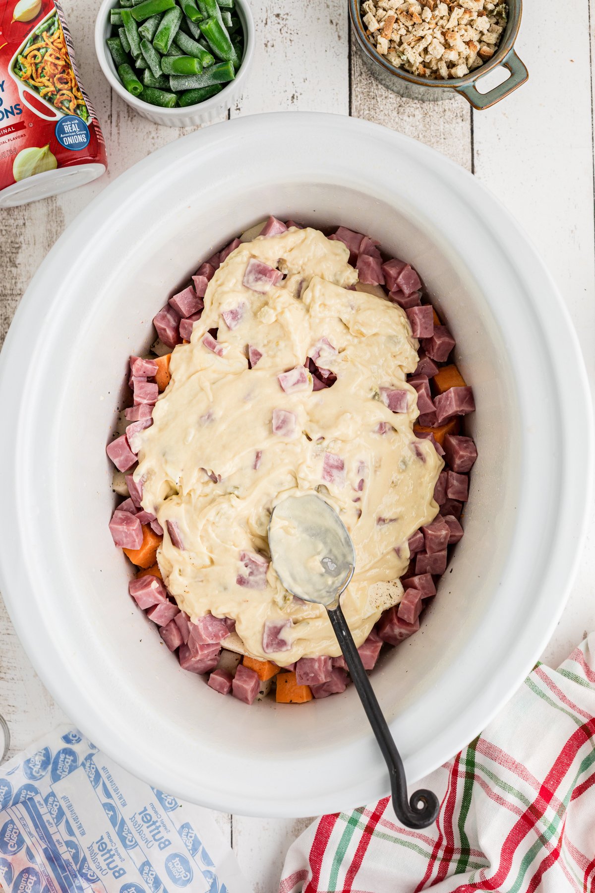 Cream of celery soup being added to ingredients in a slow cooker.