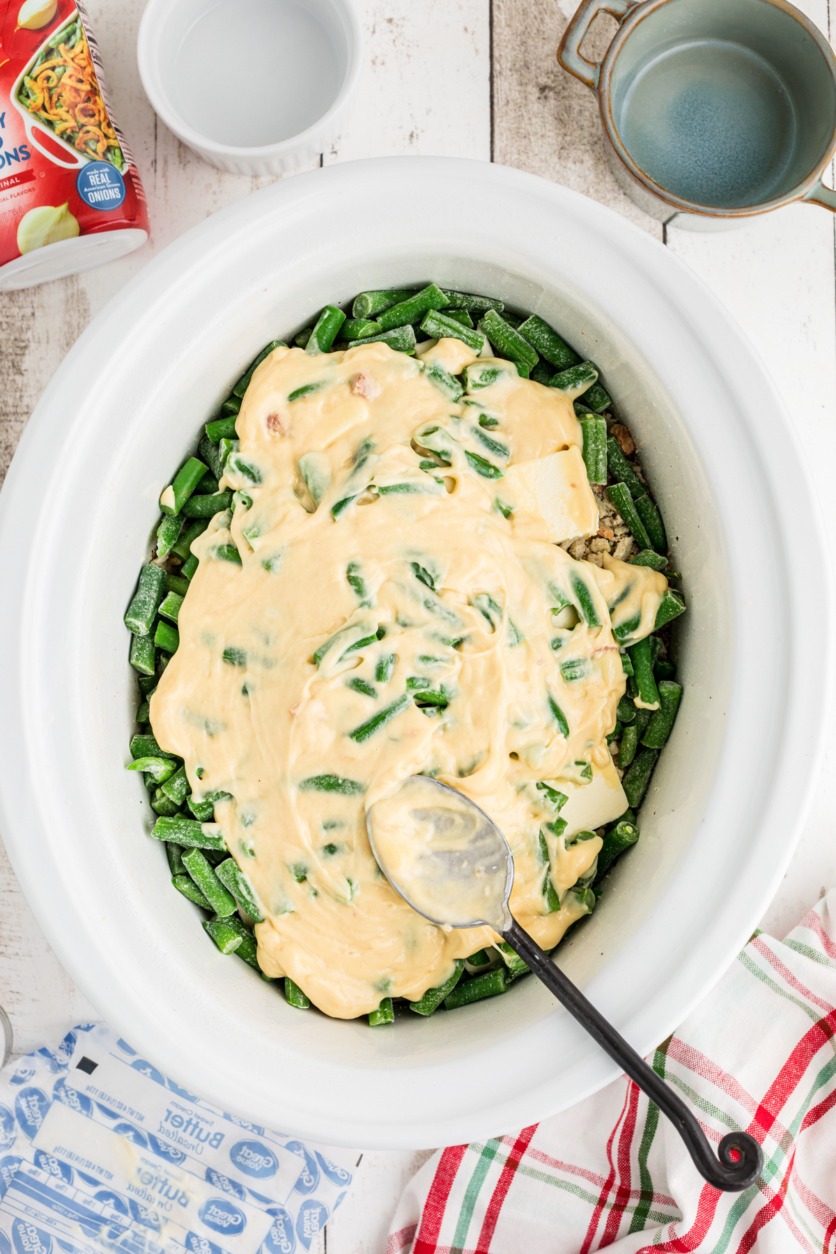 Cream of chicken soup being added to ingredients in a crockpot.