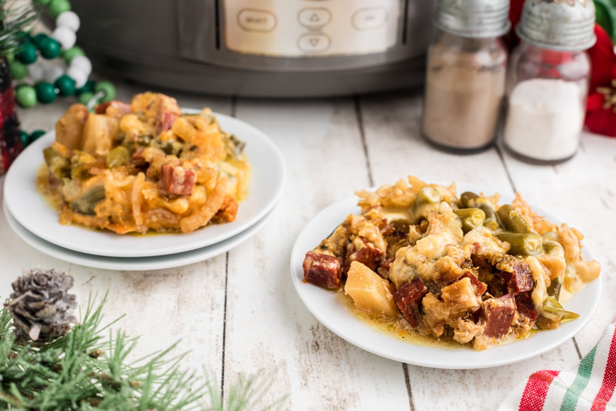 Two plates of slow cooker Christmas casserole in front of a crockpot.