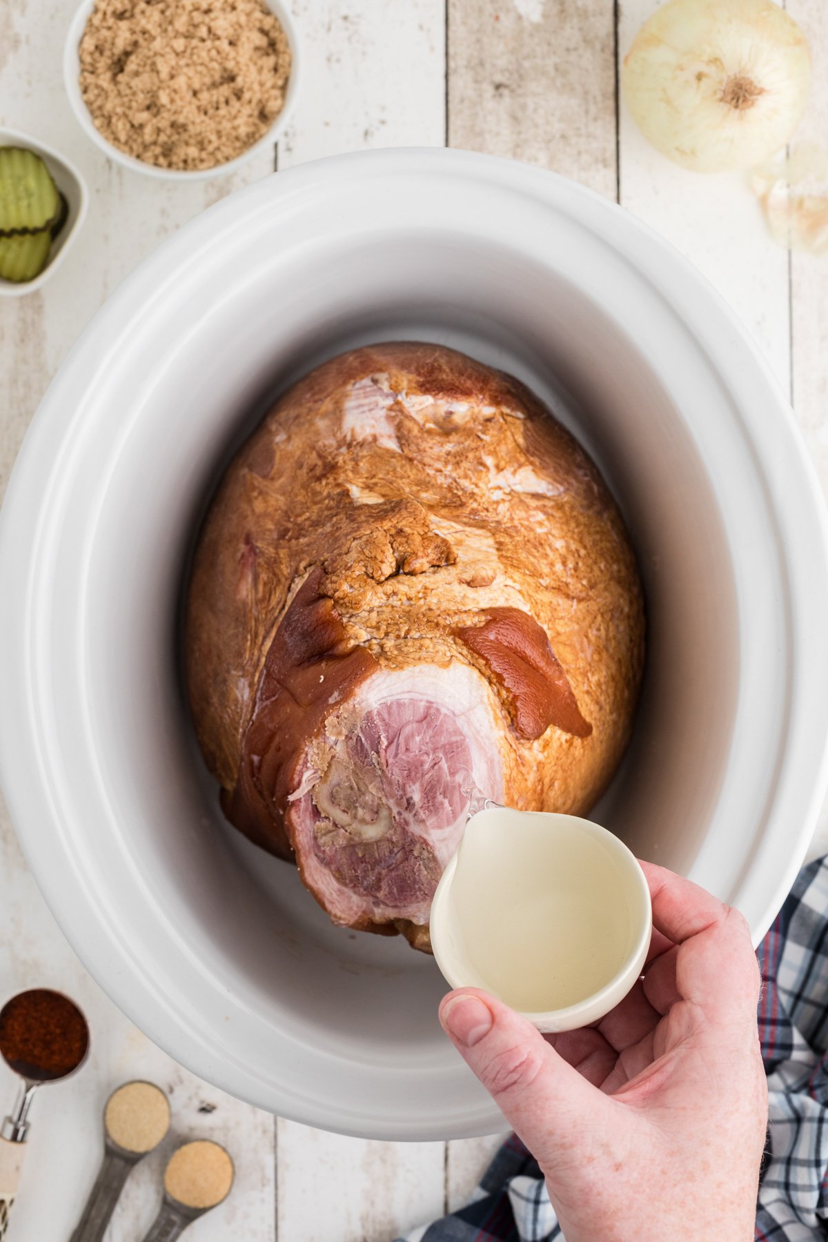 adding water to a picnic ham in a slow cooker.